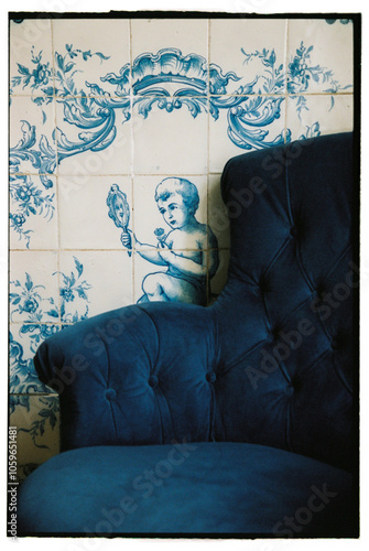 A blue armchair in front of a tiled wall photo