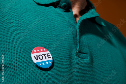 man wears a vote badge pinned to his polo shirt
