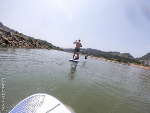 Man is enjoying stand up paddle boarding on a sunny day photo