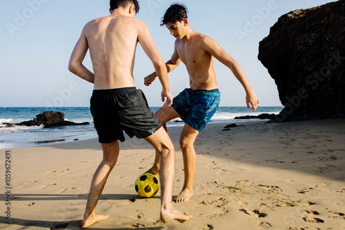 Athletic teenagers play a friendly game of soccer on the beach