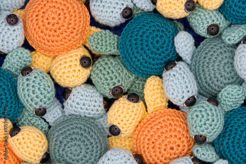 Close up above view on hand made crochet turtles in yellow and orange and greens and turquoise an blue crochet background.