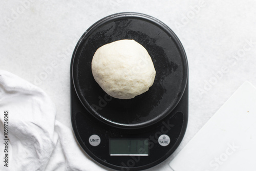 Overhead view of challah dough on a black kitchen scale, top view of homemade challah bread dough being weighed on a scale, process of making challah photo