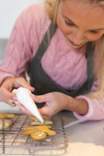 Christmas time, Decorating gingerbread cookies with icing at home, woman enjoying holiday baking photo