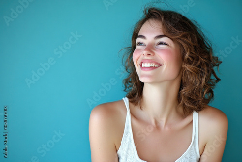 Woman with a bright smile against a colorful sunset backdrop, standing on a sandy beach with waves gently crashing in the background. photo