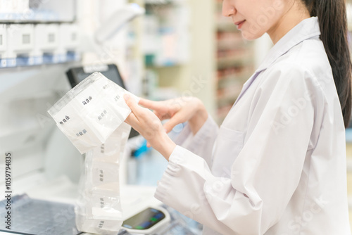 Obraz na plátně 薬局・ドラッグストアで自動分包機を使って粉薬・調剤・処方箋を作る薬剤師