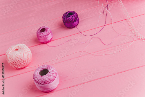 A roll of pink and purple skeins of thread on a wooden pink surface, perfect for decorating, gift wrapping and sewing. photo