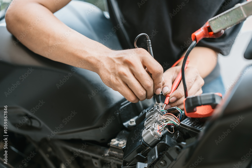 Fototapeta premium Motorcycle mechanic check motorcycle electrical system find wiring problems using a multimeter. work in garage, motorcycle repair concept ,