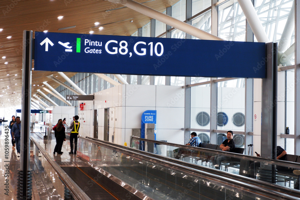 Fototapeta premium KLIA T1 or Kuala Lumpur International Airport Terminal 1 boarding gate signage on top of the moving walkways or travelator and people in the waiting area for international flight or delay in flight. d