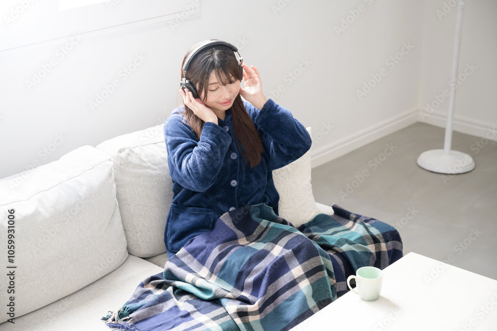 Fototapeta premium ヘッドフォンをつけて音楽を聴く歌う若い女性の全身のイメージの広角 コピースペース やや俯瞰