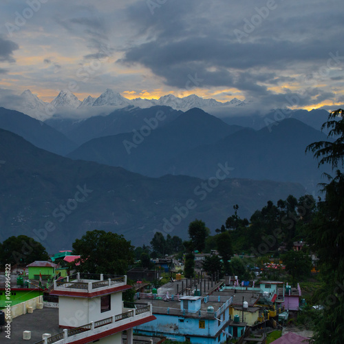 Panchachuli peaks seen from munsiyari uttarakhand during sunrise. Snow covered Himalayan mountains with clouds drifting around. Houses of munsiyari in front photo