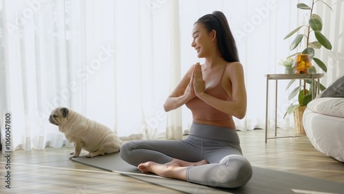 Woman practicing yoga at home with cute dog nearby. photo