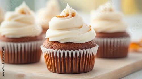 Three cupcakes with frosting on top are sitting on a wooden table