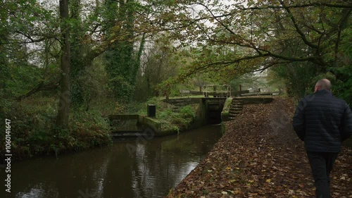 STOKE-ON-TRENT, STAFFORDSHIRE, ENGLAND - OCTOBER 30 2024: A man wearing dark clothes walking on the towpath on the Caldon Canal during autumn. photo