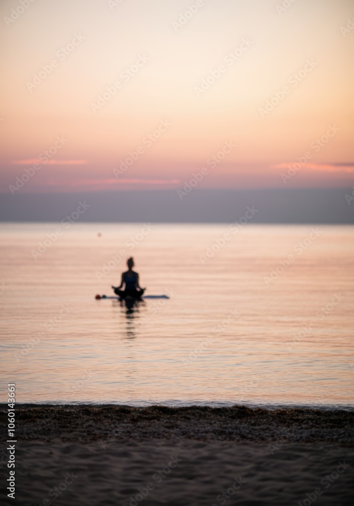 Fototapeta premium Serene meditation at sunset on a paddleboard by tranquil sea horizon