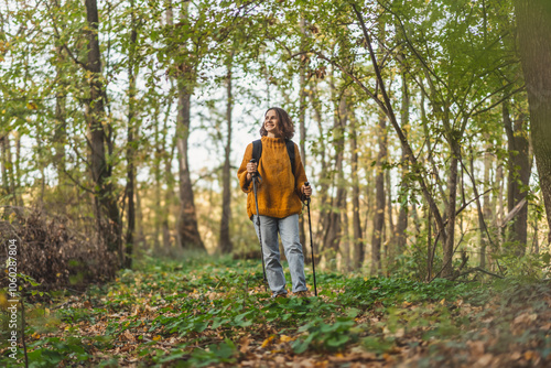 Woman with backpack and trekking poles hiking over the autumn forest