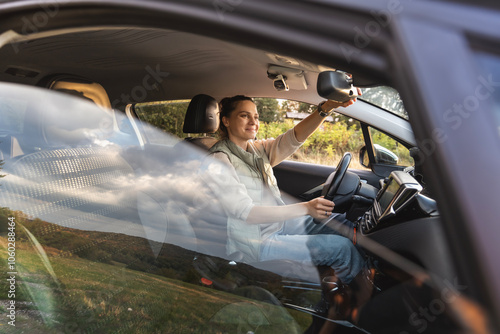 Obraz na płótnie Young female driver adjusting rear view mirror while sitting in car w salonie