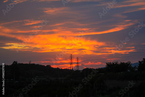 A dramatic sunset sky with colourful glowing clouds and a silhouetted landscape below