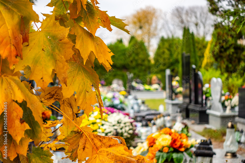 Graves with candles during the All Souls' Day celebration on November 1st. Golden, autumn leaves in the foreground. Photo taken during the day in natural light