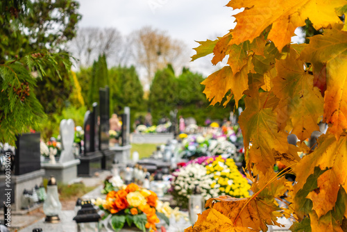 Obraz na płótnie Graves with candles during the All Souls' Day celebration on November 1st. Golden, autumn leaves in the foreground. Photo taken during the day in natural light w salonie