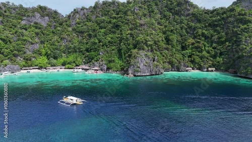 Stunning Drone Footage of a Small Boat Gliding Through Turquoise Waters Against a Backdrop of Lush Green Mountains in the Philippines – High-Resolution 4K