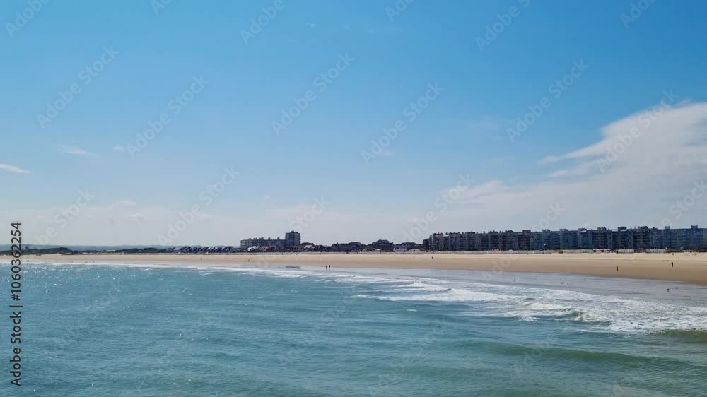 Coastal Cityscape: Serene Beachfront and Ocean Waves Under a Clear Blue Sky Coastal Cityscape: Serene Beachfront and Ocean Waves Under a Clear Blue Sky