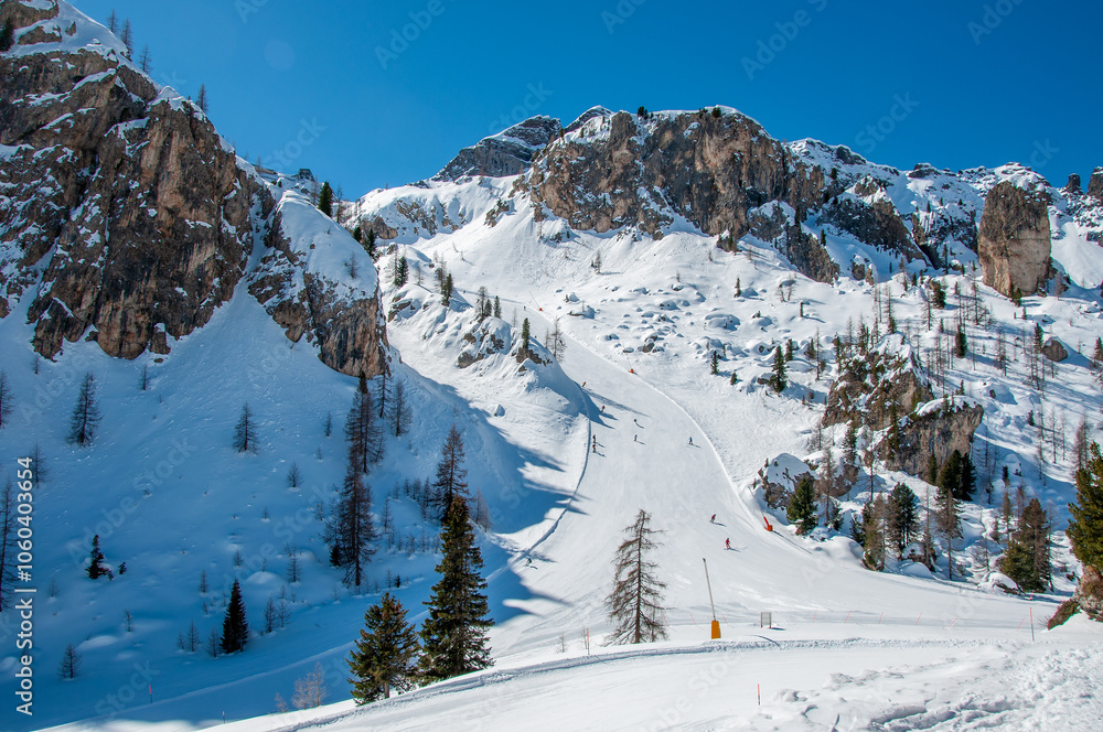 Arabba ski resort in Domites in Italy with beautiful rocks, snow and skiers on ski runs from Porta Vescovo to Arabba
