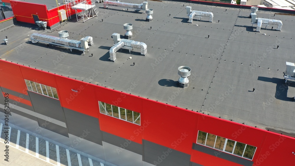 Roof infrastructure of a modern warehouse, logistics center. Exhaust, electrics, ventilation shafts, pipes, antennas on the flat roof of a warehouse. Roof of the warehouse building. Roof infrastructure of a modern warehouse, logistics center. Exhaust, electrics, ventilation shafts, pipes, antennas on the flat roof of a warehouse. Roof of the warehouse building.