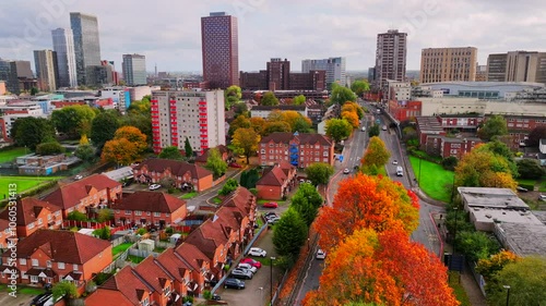 Autumnal view of Birmingham city skyline showing cars driving on a road and colorful trees.  photo