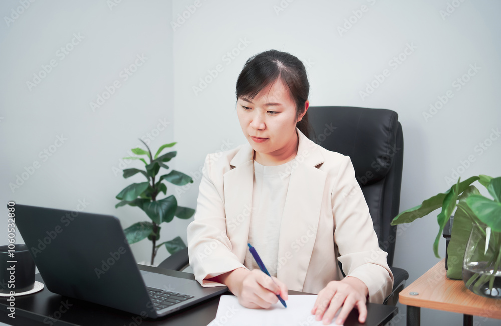 Woman typing work on laptop and checking work on paper as well Woman typing work on laptop and checking work on paper as well