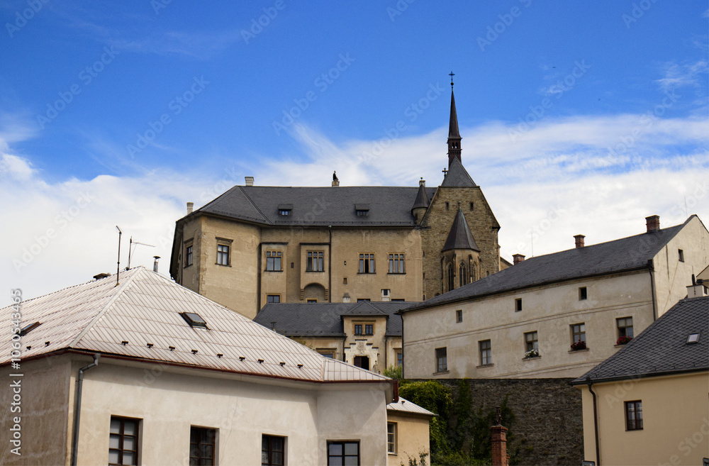 Obraz premium Photo of a castle on a hill in a part of town. A castle on top of a hill. Below the castle, houses and buildings of the castle complex. Monument, travel, tourist spot, fantasy, fairy tale.