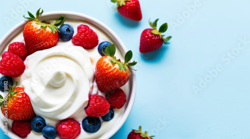 Delicious berry yogurt in a bowl, featuring fresh strawberries and blueberries on a light blue background