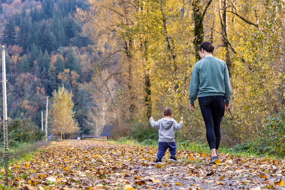 Fototapeta premium Mother and Child Walking in Autumn Forest Path