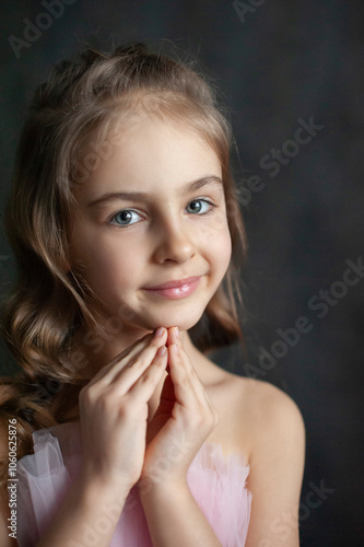 Close-up portrait of a young girl with beautifully styled hair, her hands gently folded as she dreams or makes a wish. Her soft expression and thoughtful gaze capture a magical, tender moment.