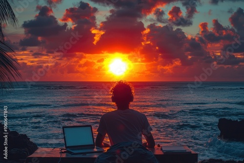 Silhouette of a Person with Laptop Watching Sunset over the Ocean