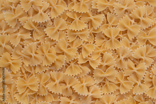 Background image of farfalle. A large pile of yellow farfalle.