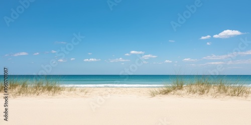 Serene beach view with golden sand and calm blue ocean under clear sky.