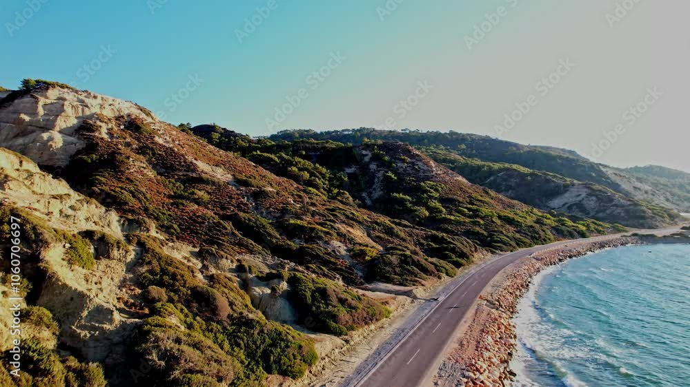 Coastal road winding alongside scenic cliffs at sunset near the shoreline Coastal road winding alongside scenic cliffs at sunset near the shoreline
