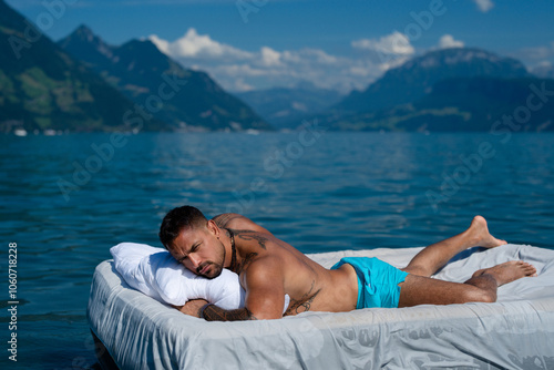 Summer Travel vacation holiday. Man rest at the lake, enjoy summer holiday. Muscular man lying on cozy Mattresses, sleep, good dreams concept. Sexy man floating on the Bed with blanket.