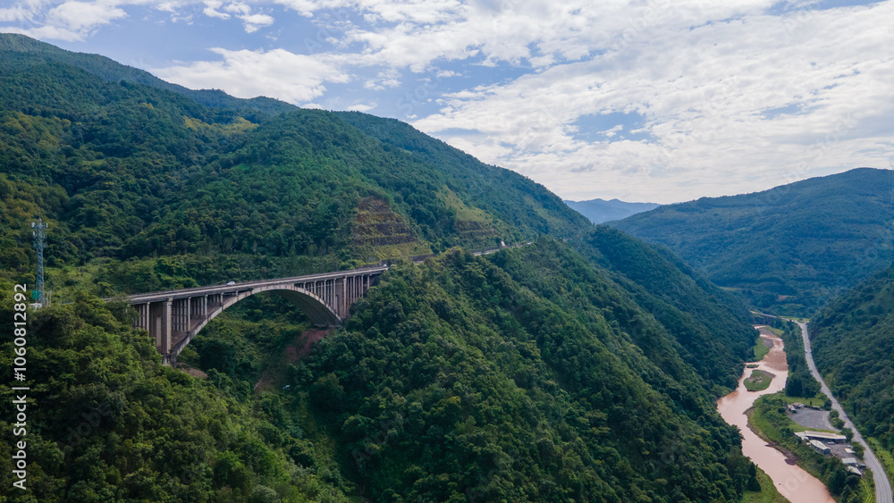 Majestic Canyon with Rushing River and Winding Mountain Highway under Blue Sky
Majestic Canyon with Rushing River and Winding Mountain Highway under Blue Sky
