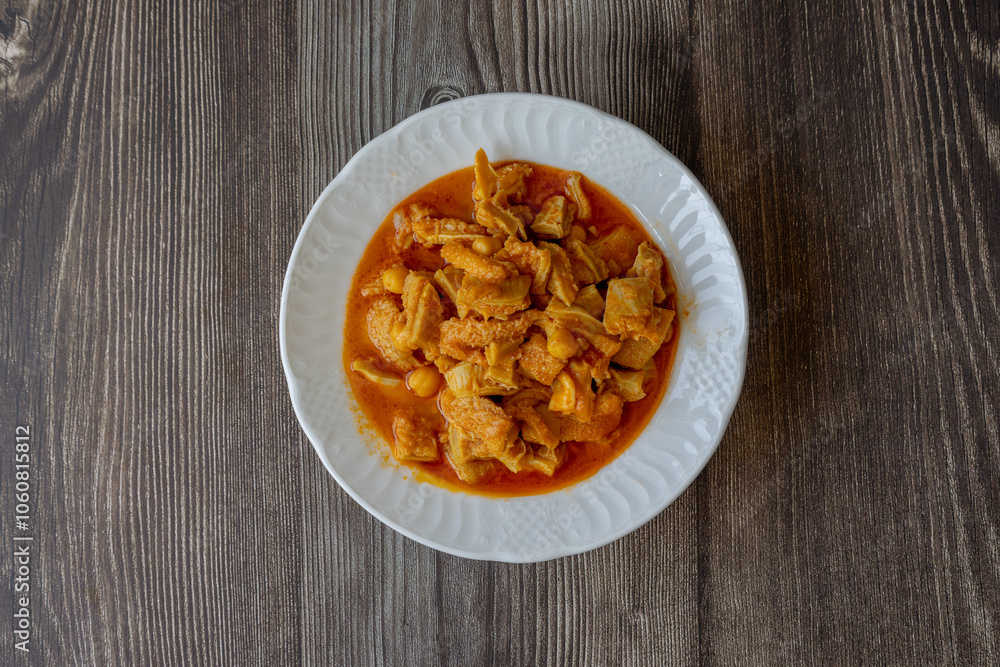 A dish from Turkish cuisine. Lamb tripe with chickpeas served on a white plate. A dish from Turkish cuisine. Lamb tripe with chickpeas served on a white plate.