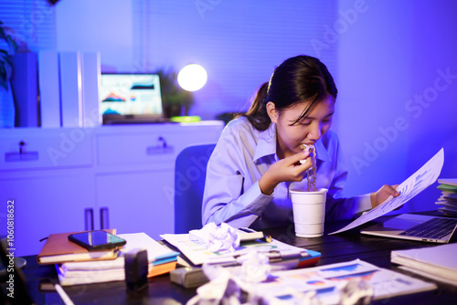 Asian woman diligently works overtime, managing a heavy workload with focus and determination. Despite the challenges, her commitment shines through as she strives and meets her deadlines.