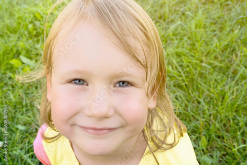 Close up of face of child girl looking at camera with happy smile on summer sunny day