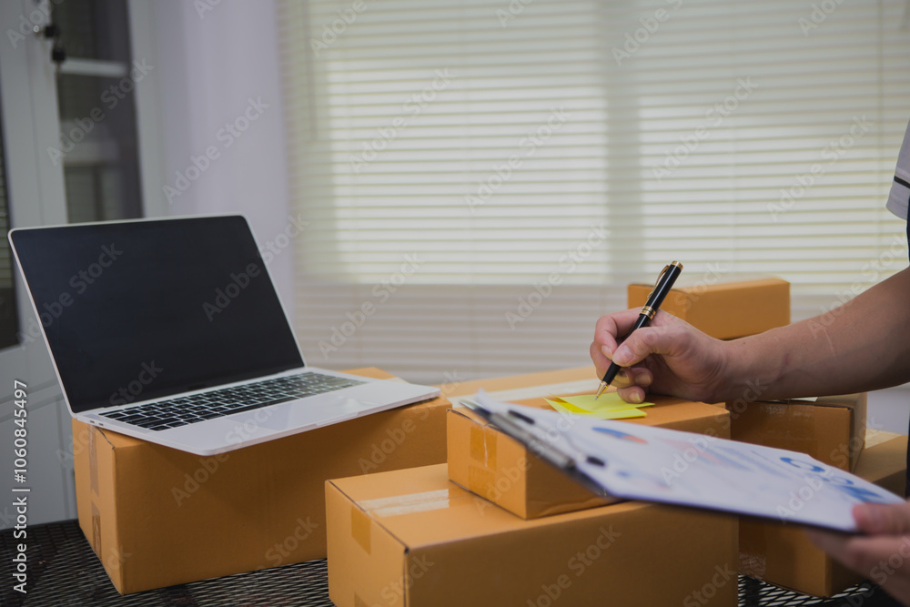 An Asian man carefully prepares a package for a customer's online order, methodically placing items in a box, sealing it securely, and attaching a shipping label for prompt delivery. An Asian man carefully prepares a package for a customer's online order, methodically placing items in a box, sealing it securely, and attaching a shipping label for prompt delivery.