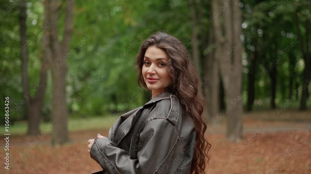 Woman in leather jacket smiles in forest. Concept of female beauty. Woman in leather jacket smiles in forest. Concept of female beauty.