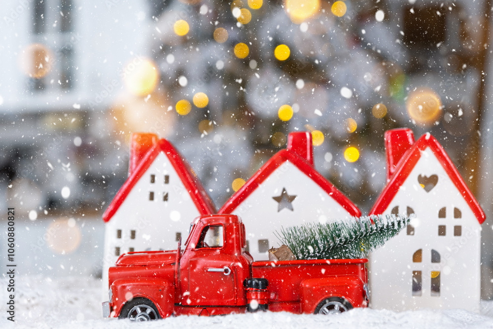 Fototapeta premium Key on Christmas tree and tiny house with a red roof with Christmas decor in red retro car on table . Gift for New Year. Insurance, moving to new house, mortgage, rent and real estate