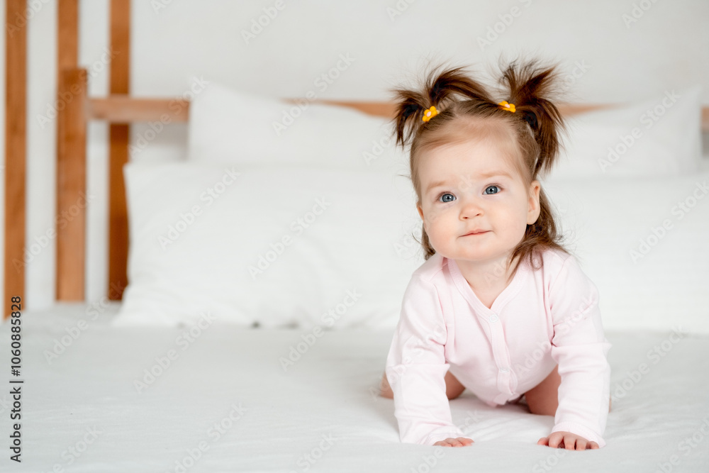Funny baby girl in pink bodysuit on the bed in the bedroom smiling or laughing, cute little baby at home, place for text Funny baby girl in pink bodysuit on the bed in the bedroom smiling or laughing, cute little baby at home, place for text