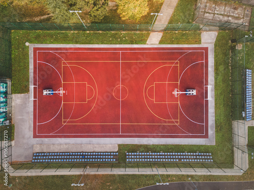 Red Basketball Court View From Above. Basketball field with white lines outdoors and stairs for spectators behind it
