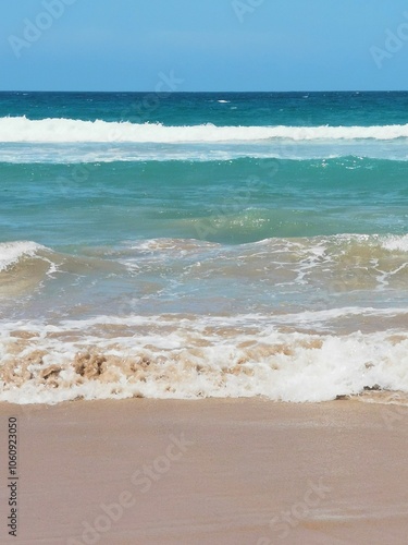 Beautiful beach scene with sand in foreground and rolling waves in background