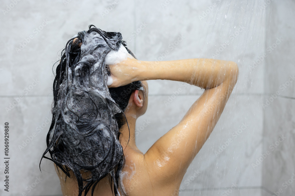 Naklejka premium Woman wash hair with shampoo and shower in bathroom