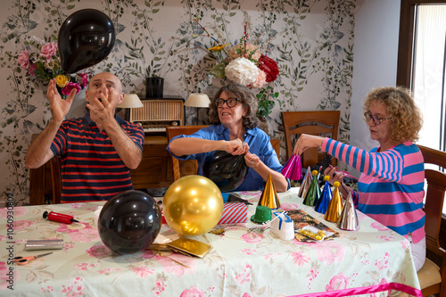 Friends smiling and inflating balloons at a decorated table for a birthday celebration